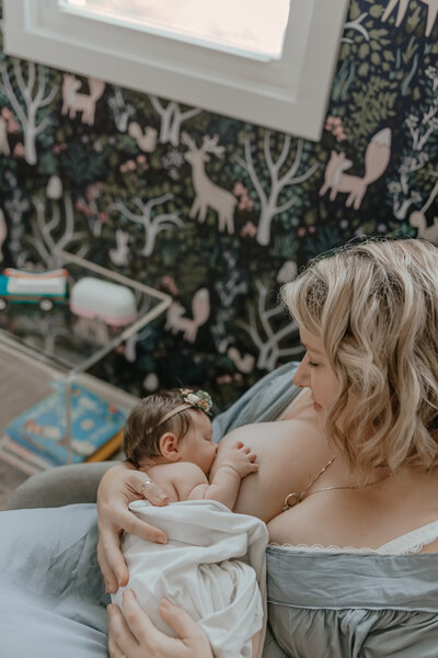 Mom breastfeeding baby during in home newborn session by Taylor Lynn Studios