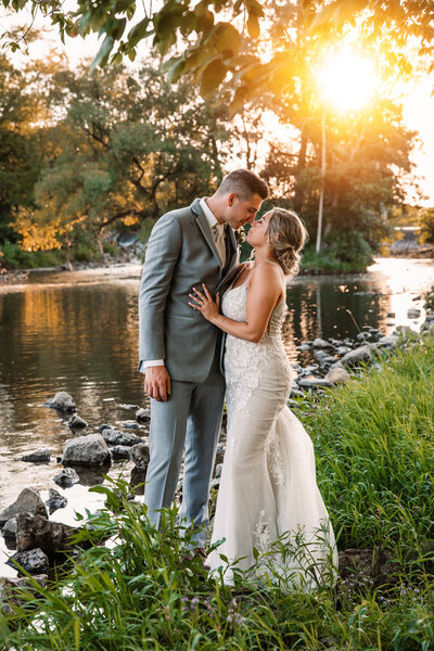 bride and groom at sunset by a river snuggled up close taking a moment to themselves at Veterans Terrace in Burlington