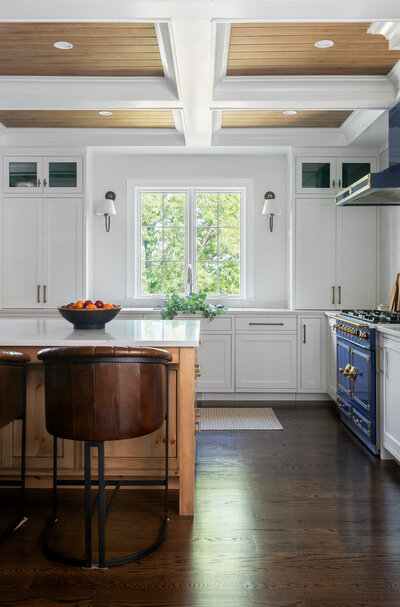 bright white kitchen with wood panel accents on the ceiling and dark blue stove