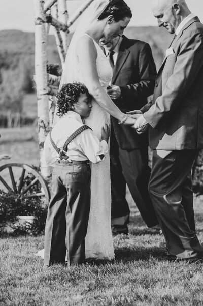 young child hugs bride during wedding ceremony