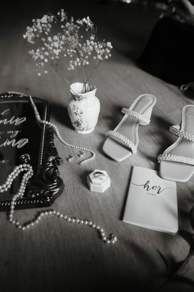 wedding photo of bridal shoes pearl necklace and wedding details plus wedding rings and vow books