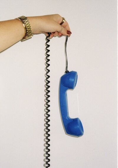 Hand holding a retro corded blue telephone