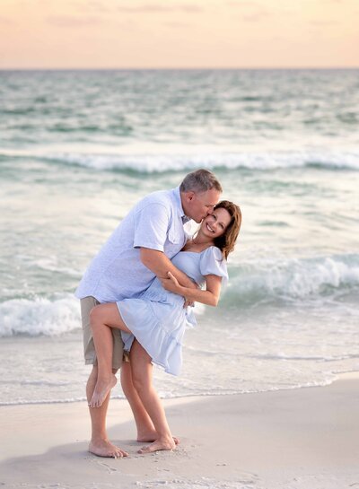 Husband dipping wife back and kissing her cheek. 