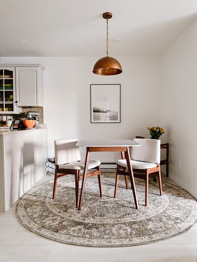 Dining nook design by Hanbury Design Co. A mid-century modern dining nook with  bistro table, copper pendant light, framed art, and bar cart.