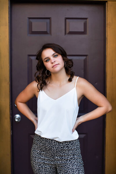 Senior picture of a girl with confident attitude in front of a purple door on Historic Commerical Street in Springfield, MO. Captured by senior photographer Dynae Levingston