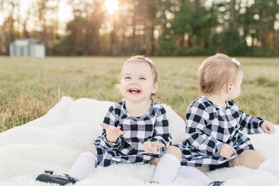 toddler sitting on blanket outside with big smile