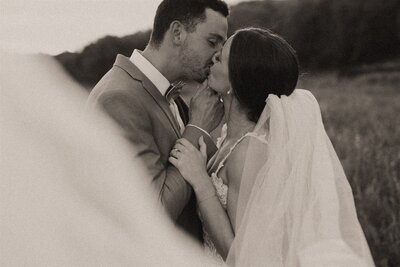 A black and white, film portrait of a Bride and groom sharing a kiss at sunset in Minnesota