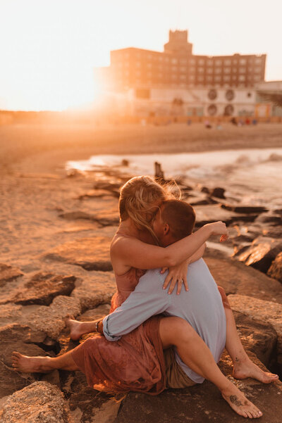 Couple sitting and hugging during their beach engagement session in Pennsylvania