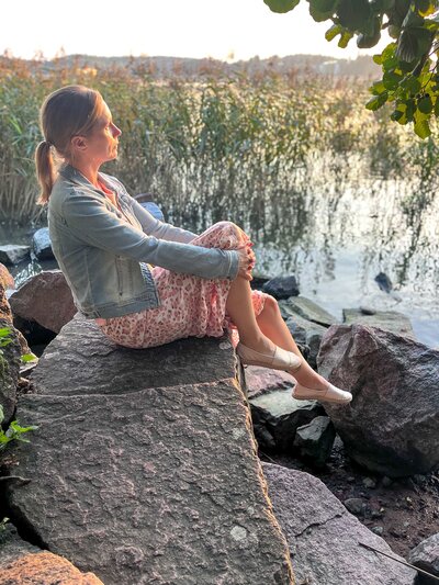 Työhyvinvoinnin valmentaja istumassa kivellä ja nauttimassa vapaa-ajasta, jonka Sinä olet Coaching valmennus tuo