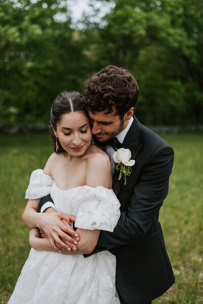 a bride and groom holding each other in a field
