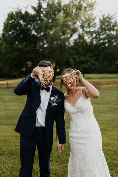 Bride and Groom holding pizza in front off their faces during their wedding day