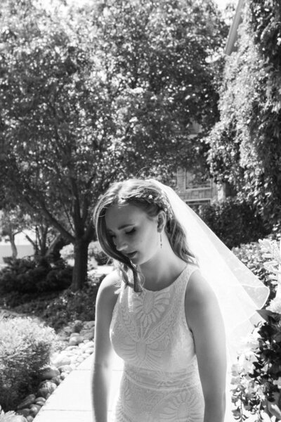 A bride looks down and off to the side as she is framed by trees.