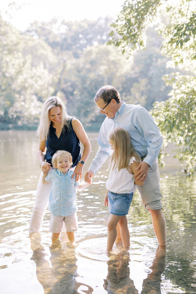 Family laughs together in a lake for portrait photos