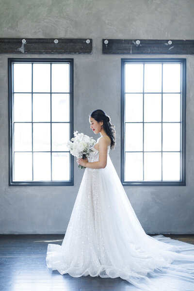 Model standing with white wedding dress and bouquet at an editorial shoot at White Space Studios in Utah.