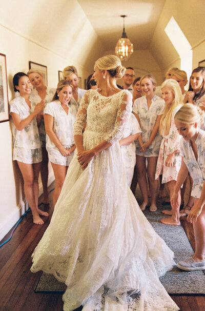 A bride surround by all her bridesmaids when getting ready for her wedding day. 