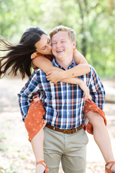 A couple is hugging each other during their engagement session in the woods at an Austin photo studio.