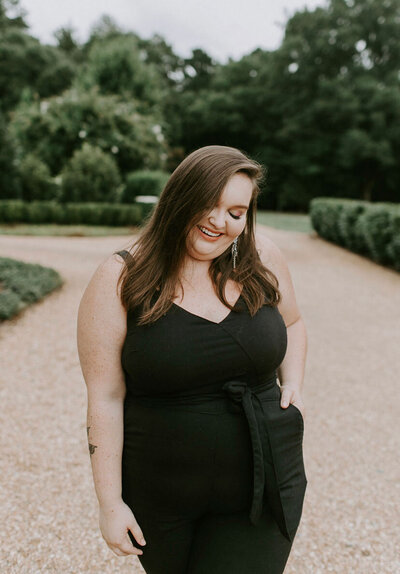 charlotte wedding photographer wearing black jumpsuit and smiling at the andrews farm in charlotte nc