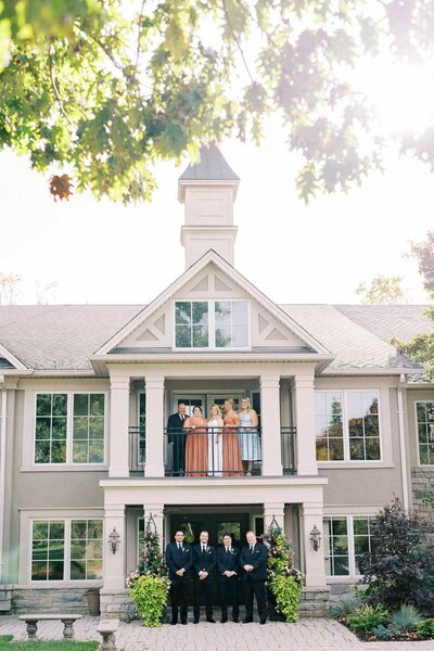 Group portrait of wedding party with groomsmen below and bridesmaids on the balcony of Oakville venue