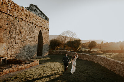 couple running off into the sunset after vow renewal at corcomroe abbey in northern ireland
