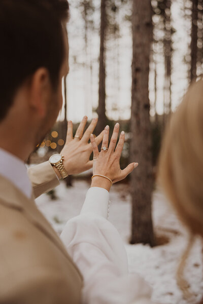Minnesota bride and groom hold their new rings up to the snowy landscape