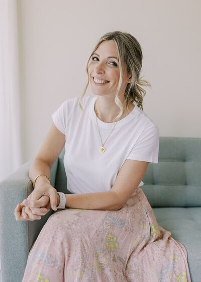 Women branding session as she sits on the couch smiling at the camera.