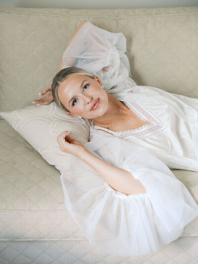 Bride gets ready for wedding and poses on white couch