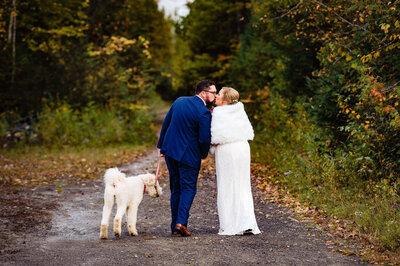 a bride and groom kissing while their dog looks at them during their fall Ottawa wedding