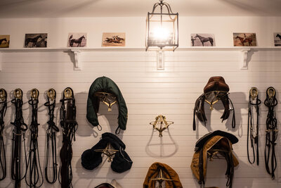 A chic stable designed tack room with saddles and bridles and a chandelier
