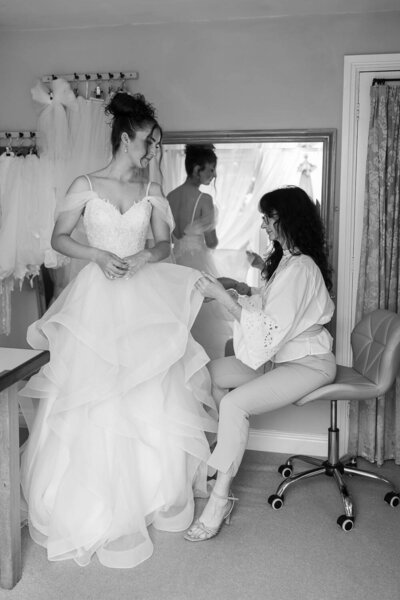 Bridal seamstress adjusting a layered tulle wedding gown on a bride during a custom dress fitting
