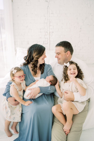 family of five cuddle together and smile at the new baby boy