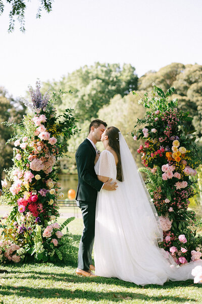 bride and groom pose in front of window on wedding day