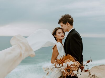 bride & groom kissing by the ocean
