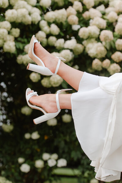 Waist Down image of a Bride and Groom Embracing, the bride is holding her blush, white and green wedding bouquet by her side