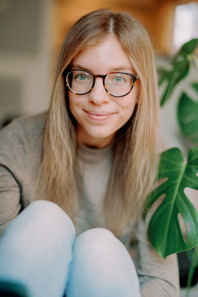 A person with glasses leaning forward and smiling 