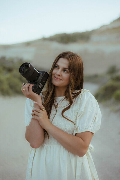Pointing her camera off to the side and slightly upwards, Brittney smiles as she also looks in that direction.