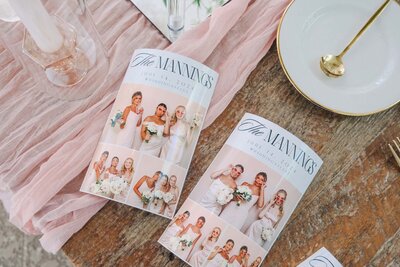 Flat lay of photo strips with bridal party images placed on blush linen alongside wedding place settings.