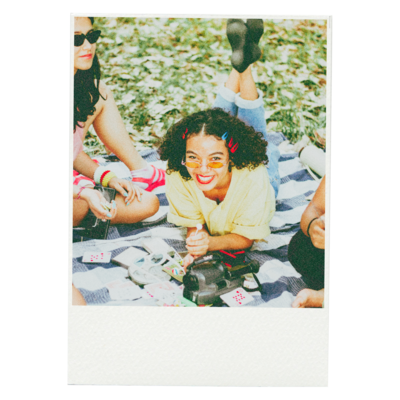 Three girls sitting on a blanket in a park, laughing and sharing a joyful moment together.