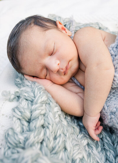 newborn in romper sleeping on hand made blanket