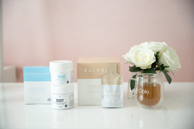 Oola supplement collection for mind body and balance with a mug of tea and flowers