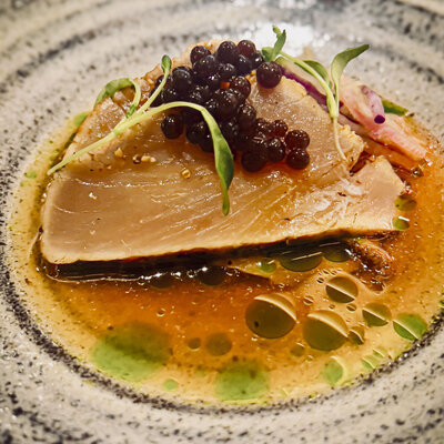 A serving of fish on a plate, artfully accompanied by black caviar, highlighting a refined dining experience.