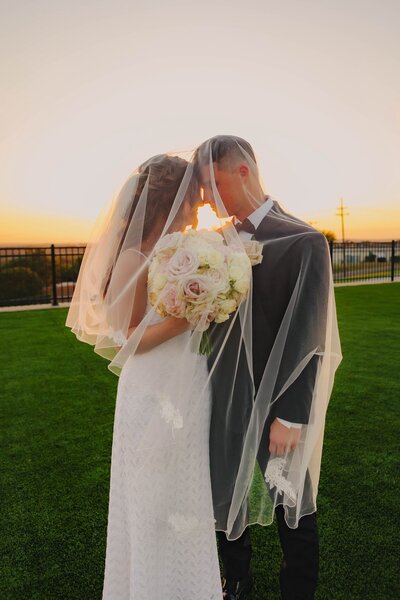 bride and groom share a kiss under the veil at dallas texas wedding
