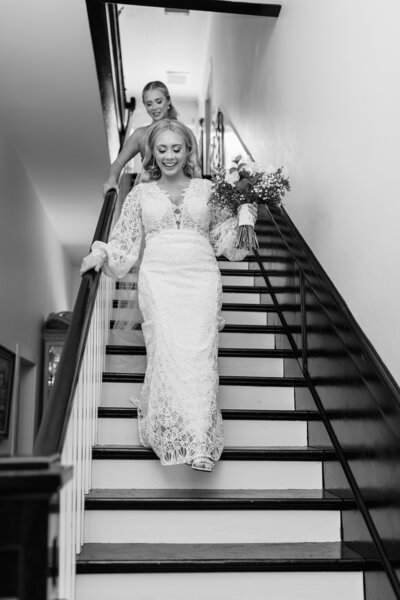 A bride and her sister walk down the stairs.