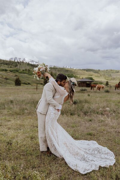 bride and groom kissing after saying vows in a utah desert with horses and mountains in background