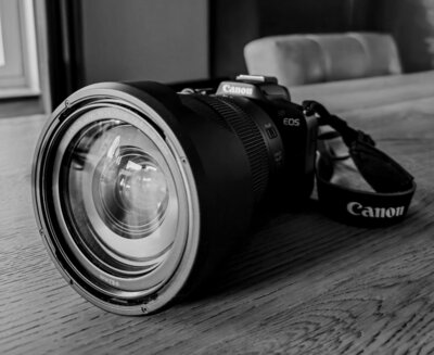 Zwart-wit afbeelding van een cameralens, met een deel van de camerabody zichtbaar.