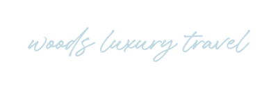 Text based logo in script font "Woods Luxury Travel"