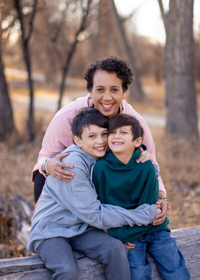 mother and her two sons sitting on a log hugging each other