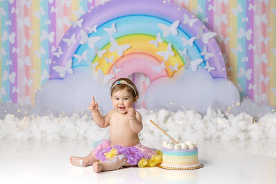 Baby girl with a fruit themed first birthday cake smash