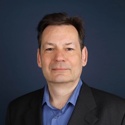 Portrait von Detlef Borst von Envidatec vor dunkelblauem Hintergrund.