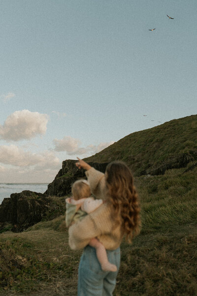 Family photoshoot in Sawtell with a mother holding her daughter and pointing at the sky