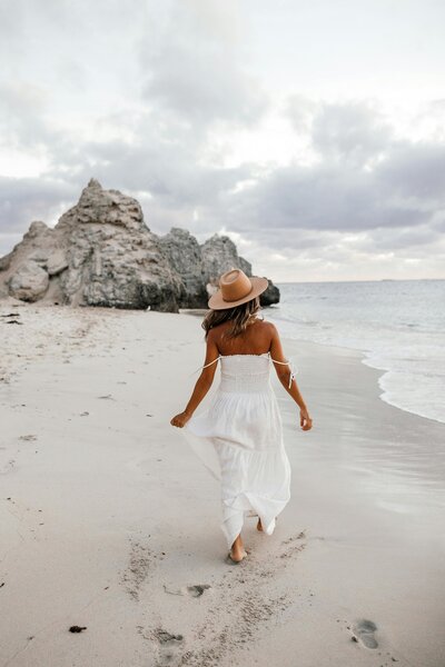 woman running on beach in white dress